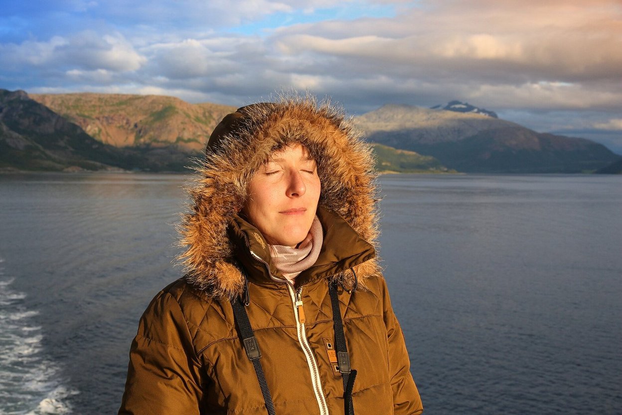 A woman with her eyes closed enjoying the evening sun on a ferry