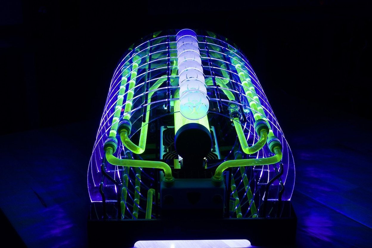 Futuristic glowing tube structure with neon green and blue lights in a dark setting.