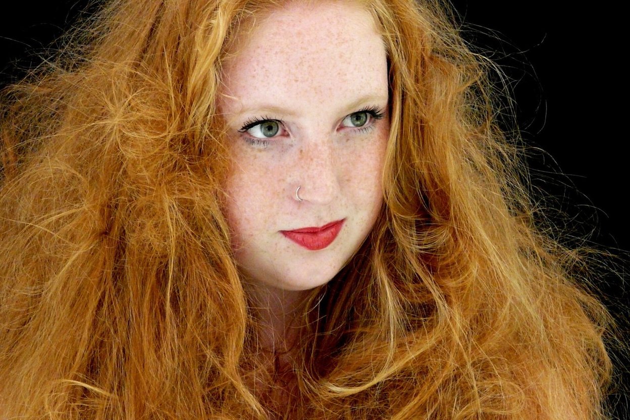 A young woman with long curly red hair and freckles