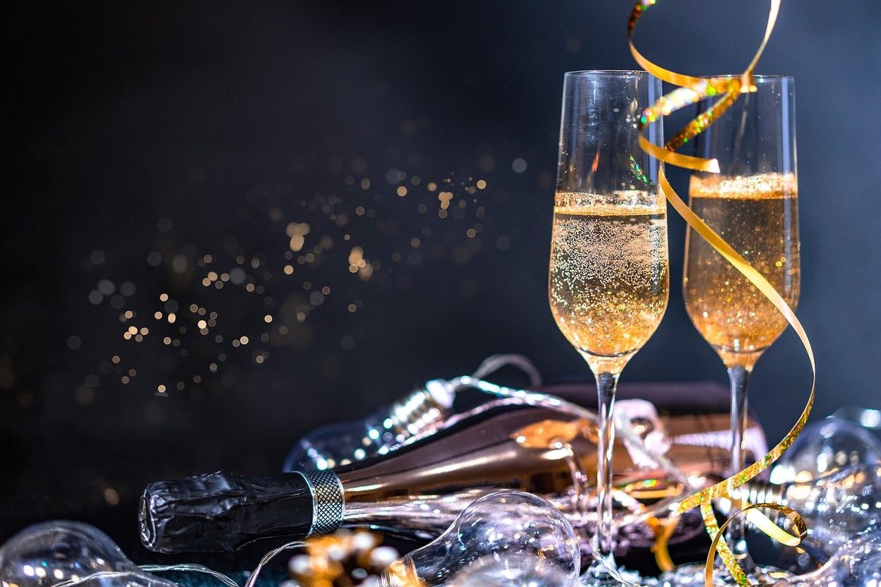 Two champagne flutes tied with a gold ribbon, raised for a wedding toast.