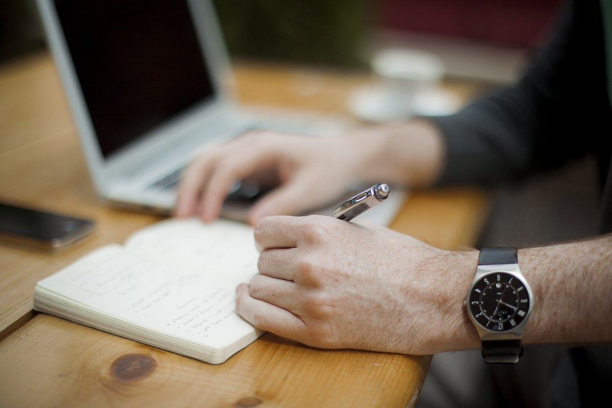 A left hand writing in a notebook