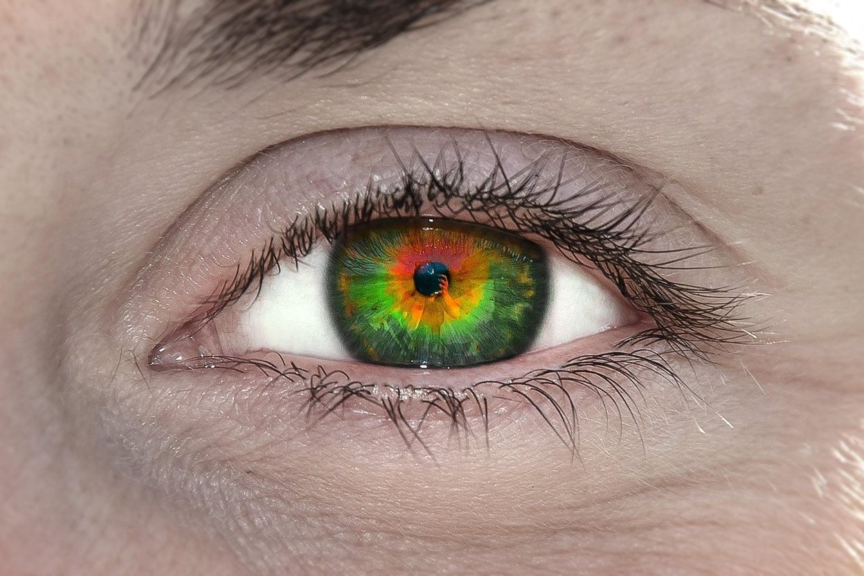 Close-up of a human eye with a vivid green, red and orange iris.